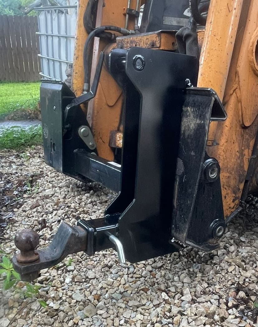 Heavy-duty equipment attachment with hitch mounted on a construction vehicle in gravel.